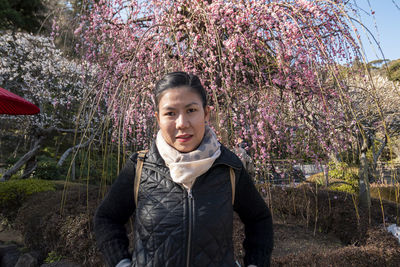 Portrait of young man standing by cherry blossom