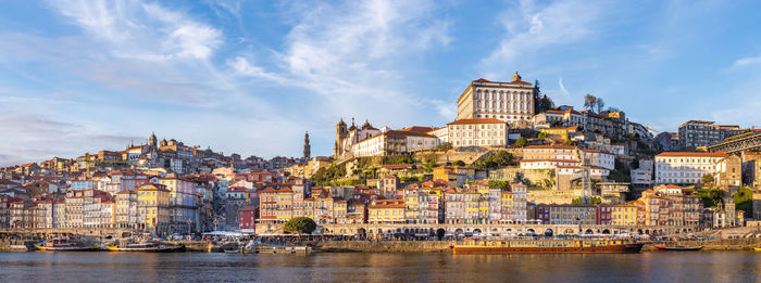 Buildings by river against sky in city