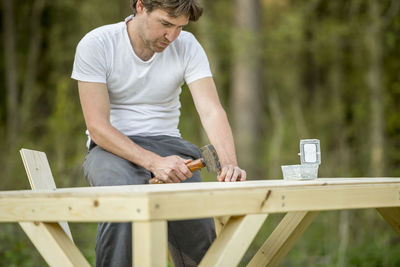 Man holding umbrella on wooden table in yard