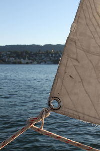 Close-up of sailboat in sea against clear sky