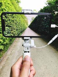 Close-up of hand photographing while holding mobile phone on monopod