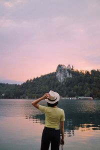 Rear view of man looking at lake against sky