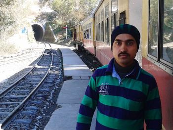 Portrait of young man standing on railroad track