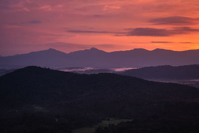 Mountains range misty shadow with dramatic colorful sunset sky at dusk from flat angle