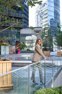 Portrait of young woman sitting on railing