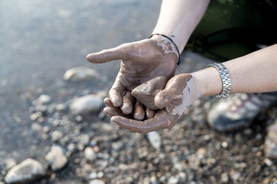 Woman putting mud on hands and face while enjoying outdoors in nature.