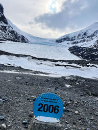 Text on snow covered mountain against sky