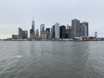 Modern buildings by river against sky in city