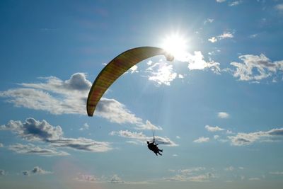 Low angle view of people paragliding against sky