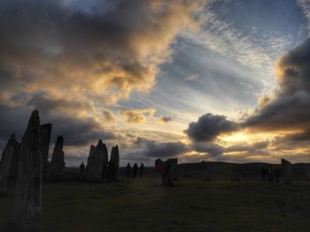 Panoramic view of people on field against sky during sunset