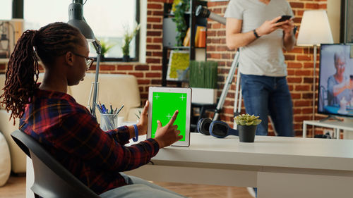 Side view of young woman using digital tablet while standing in library