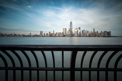 View of cityscape by sea against sky