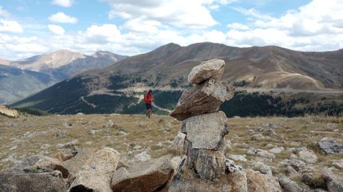 Rear view of woman standing on rock against sky