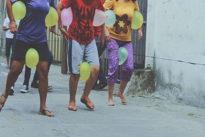 Low section of girls walking with water bombs on road