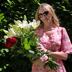 Woman standing by pink flowering plant