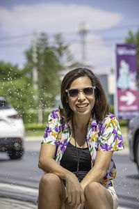 Portrait of smiling young woman sitting on car