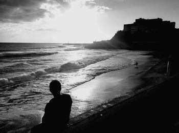 Rear view of silhouette man at beach against sky