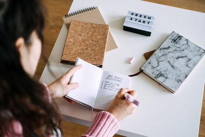 Midsection of woman writing in book