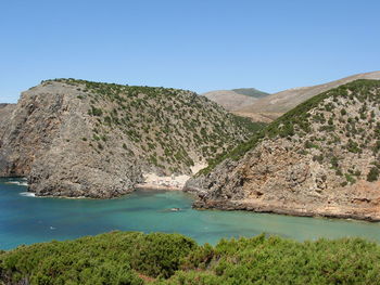 Scenic view of lake and mountains against clear blue sky