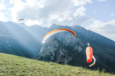 People paragliding on mountain peak against sky