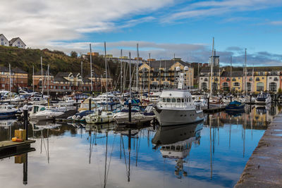 Sailboats moored at harbor against sky