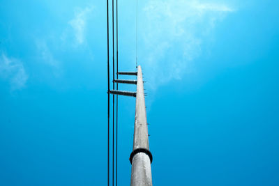 Low angle view of electricity pylon against blue sky