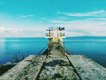 Pier on sea against cloudy sky