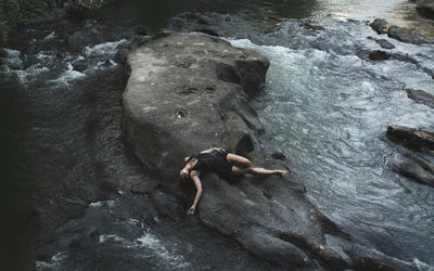 Full length of shirtless man on rock in sea