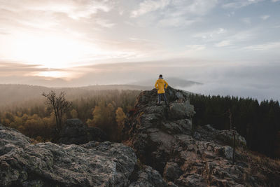 Man standing on rock against sky