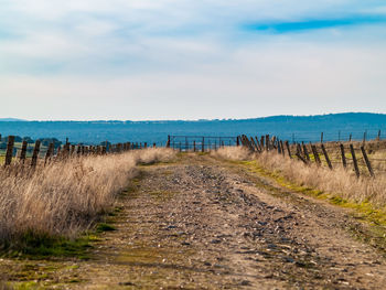 Footpath leading towards sea against sky