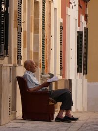 Full length of man sitting on seat in building