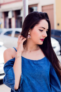 Young woman wearing earring while standing outdoors