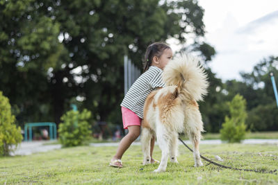 Portrait of young woman with dog on field