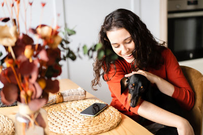 Side view of young woman with dog at home