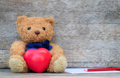 Close-up of teddy bear with heart shape against wall