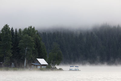 Wooden cabin on lake shore on foggy morning in british columbia