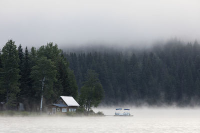 Wooden cabin on lake shore on foggy morning in british columbia