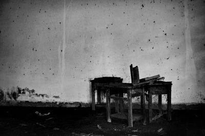 Empty chairs and table against wall in old building