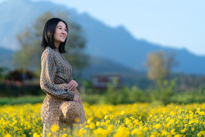 Young woman with yellow flower in field