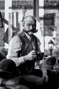 Portrait of mature man having coffee while sitting at barber shop