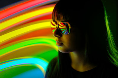 Close-up of girl wearing sunglasses against illuminated lights