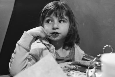 Girl looking away while having food at home