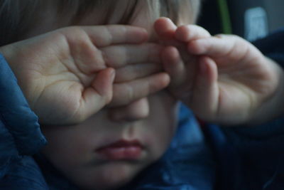 Close-up of boy rubbing eyes with hands