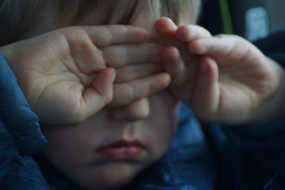 Close-up of boy rubbing eyes with hands