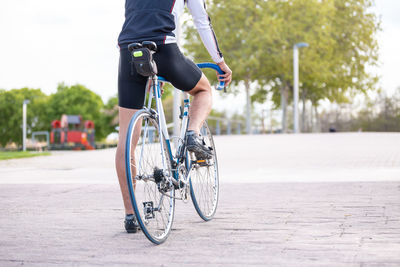 Low section of male athlete with bicycle on footpath in city