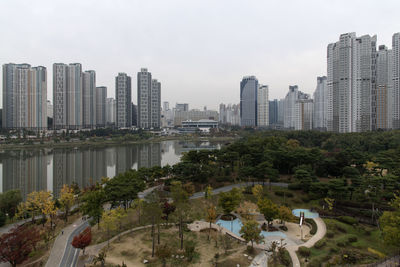 Trees and buildings in city against sky