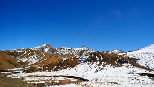 Scenic view of snowcapped mountains against clear blue sky