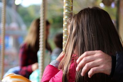 Cropped hand of father by girl on carousel