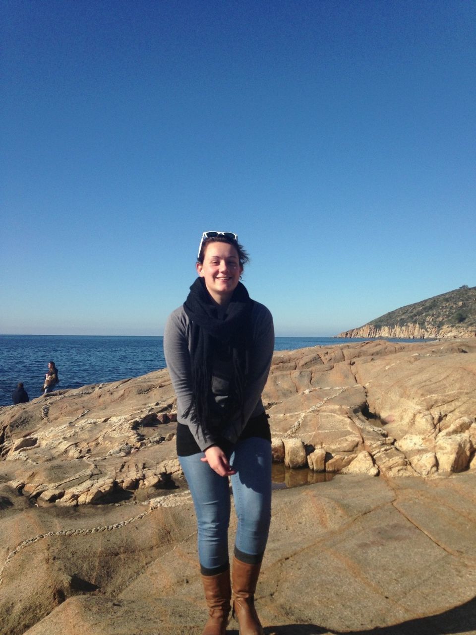 beach, clear sky, copy space, lifestyles, leisure activity, sea, sand, young adult, person, casual clothing, shore, blue, looking at camera, portrait, full length, vacations, standing, smiling