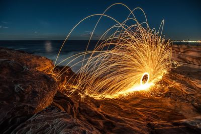 Light painting at sea shore against sky during night